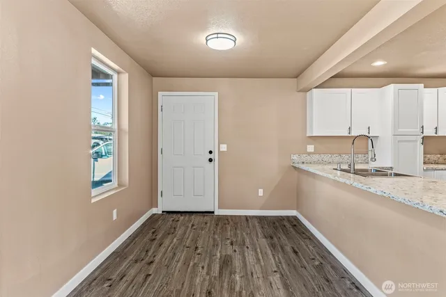 a view of a kitchen with a sink and dishwasher with wooden floor