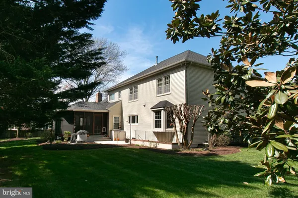 a view of a white house with a big yard plants and large trees