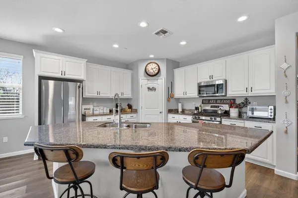 a kitchen with stainless steel appliances granite countertop a stove top oven a sink a dining table and chairs