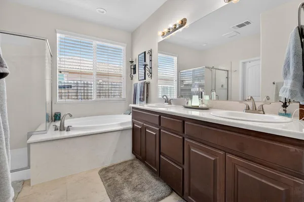 a bathroom with a bathtub sink double vanity and mirror