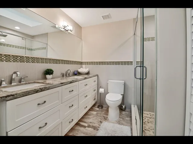 a bathroom with a granite countertop sink a toilet and a mirror