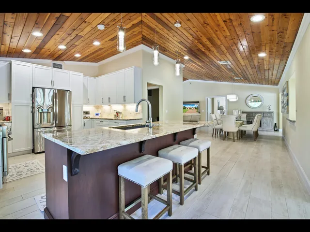 a kitchen with granite countertop a table chairs stove a refrigerator and cabinets