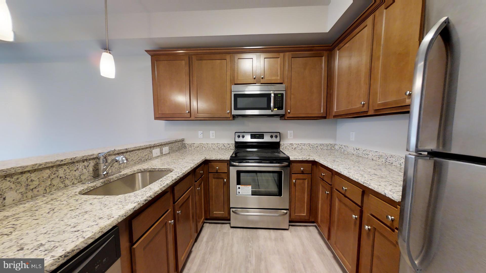 a kitchen with stainless steel appliances granite countertop a sink stove microwave and refrigerator
