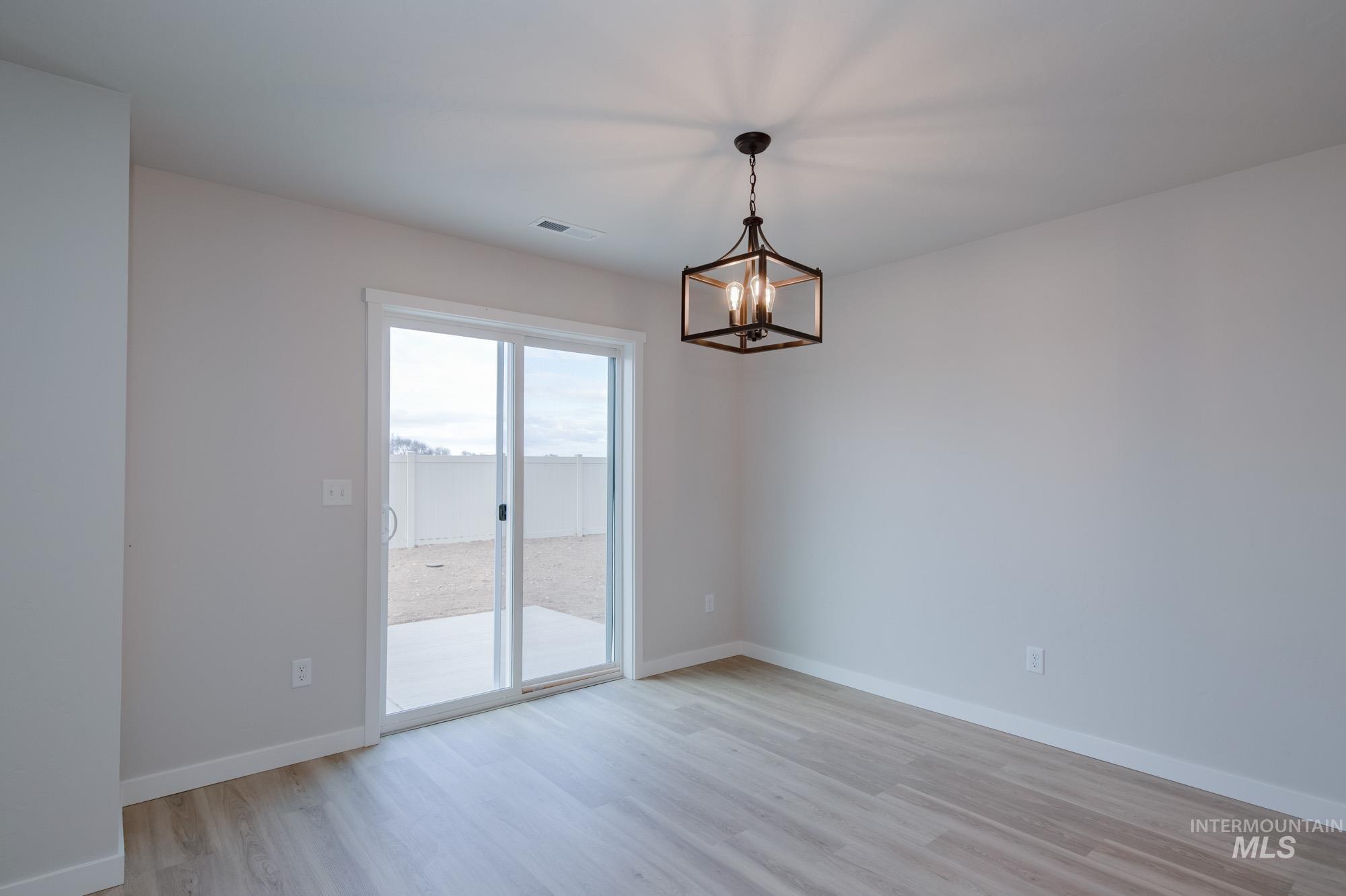 3089 South Maple Rnch Way Nampa, ID 83686 - Photo 11 of 22 Empty room with light wood finished floors and a chandelier