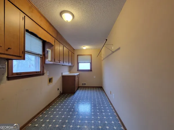 an empty room with chandelier fan and windows