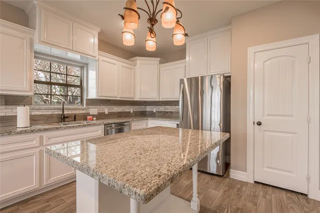 a kitchen with stainless steel appliances granite countertop a sink and a refrigerator