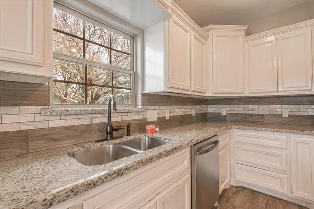 a kitchen with stainless steel appliances granite countertop a sink and a white cabinets
