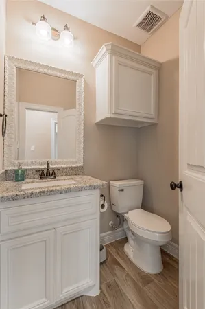 a bathroom with a granite countertop toilet sink and mirror