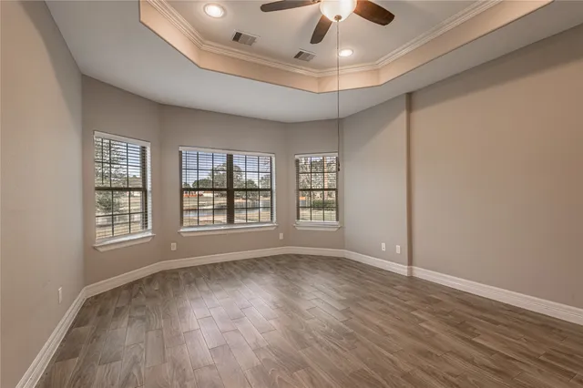 a view of an empty room with a window and wooden floor