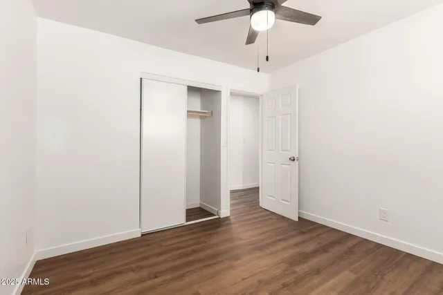 an empty room with wooden floor fan and windows