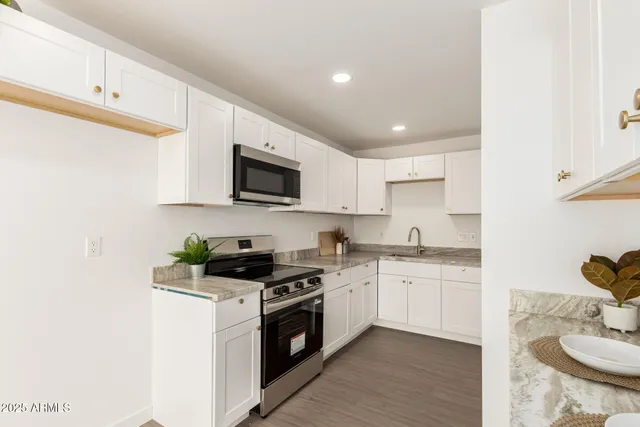 a kitchen with stainless steel appliances kitchen island granite countertop a sink a stove top oven a counter space and cabinets