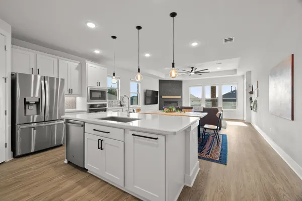 a kitchen with stainless steel appliances granite countertop a sink a stove a refrigerator and island with wooden floor