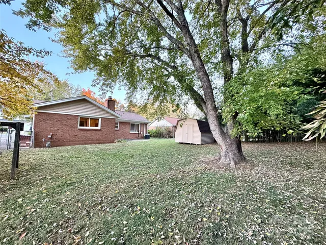 a view of a house with a yard and large trees