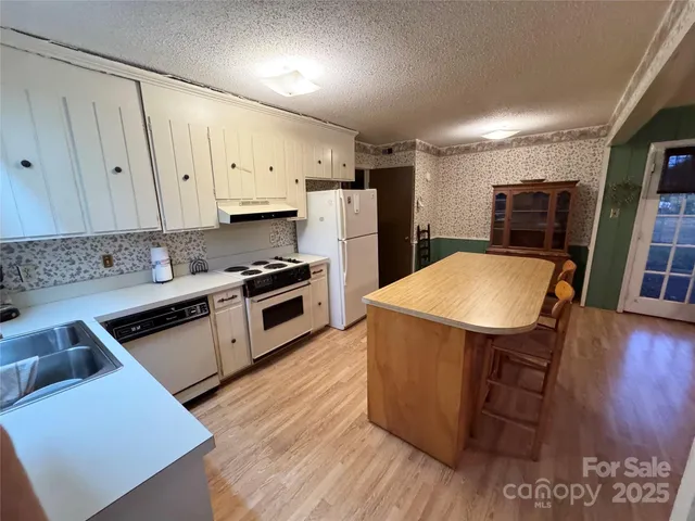 a kitchen with stainless steel appliances a stove a sink a refrigerator white cabinets and wooden floor