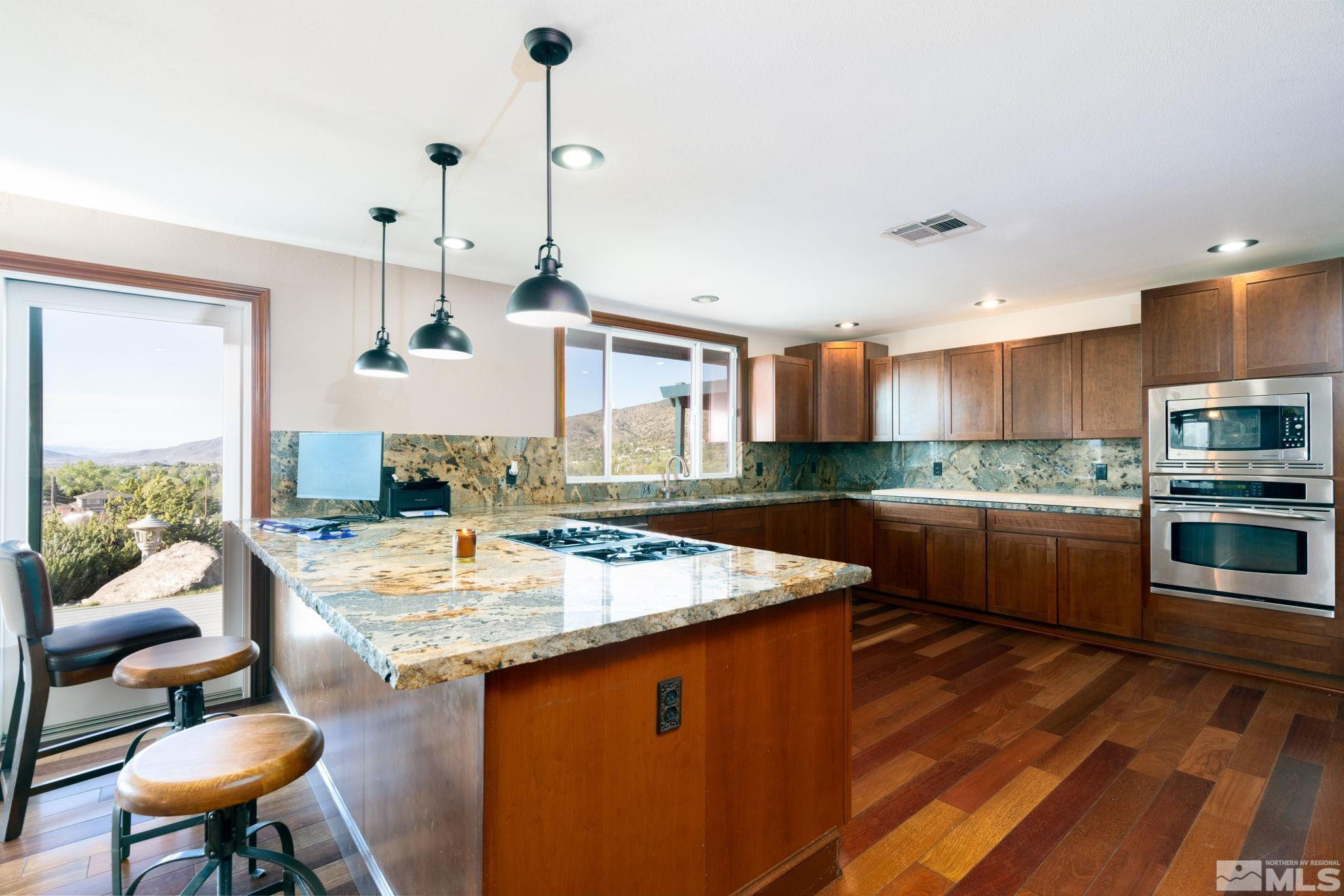 15350 Yankee Blade Road Reno, NV 89521 - Photo 3 of 27 a kitchen with a stove a sink dishwasher a kitchen island with chairs and wooden floor
