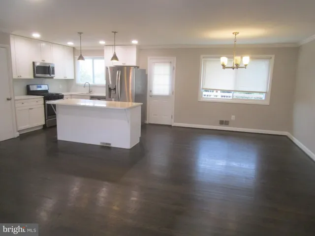 an open kitchen with kitchen island white cabinets and stainless steel appliances