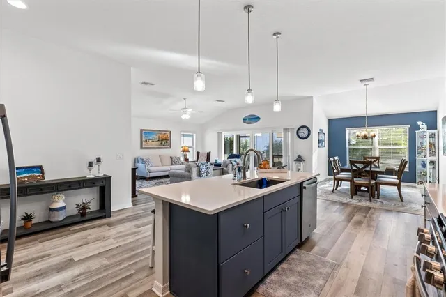 a large kitchen with stainless steel appliances a stove center island a living room and wooden floor