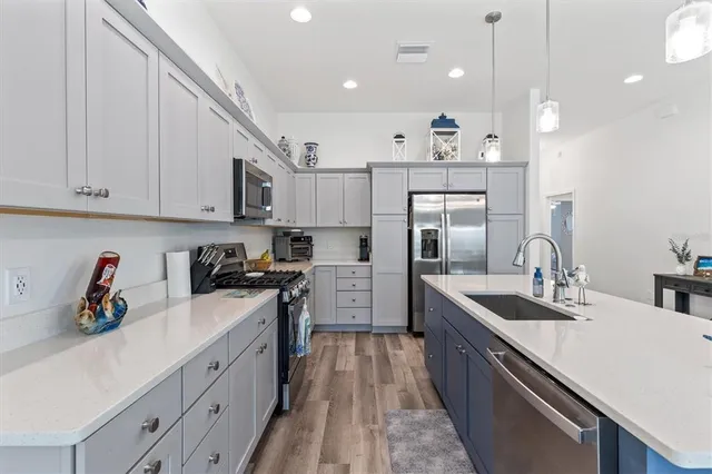 a kitchen with kitchen island white cabinets stainless steel appliances and a sink