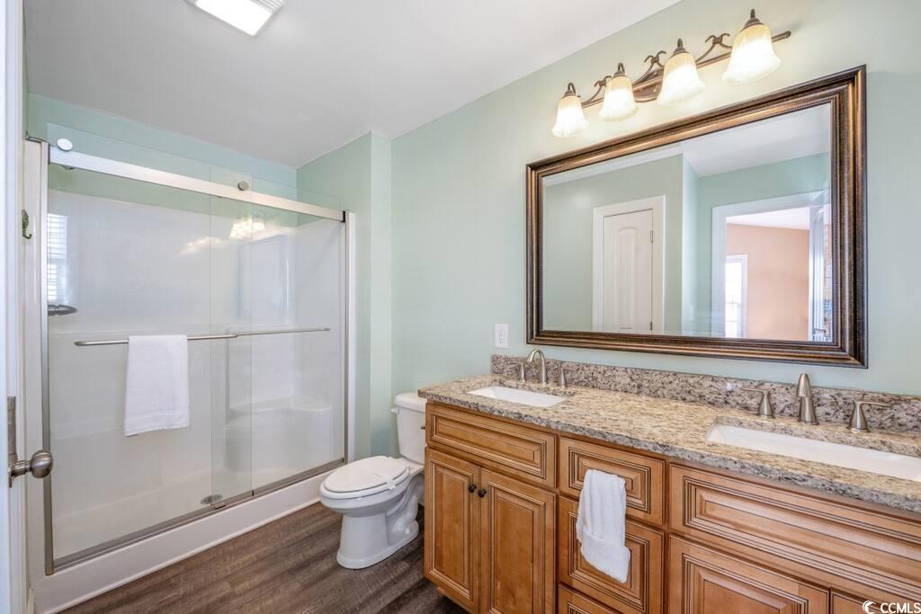 520 Caribbean Way Myrtle Beach, SC 29577 - Photo 13 of 21 Full bathroom featuring double vanity, a shower stall, and dark wood-style flooring