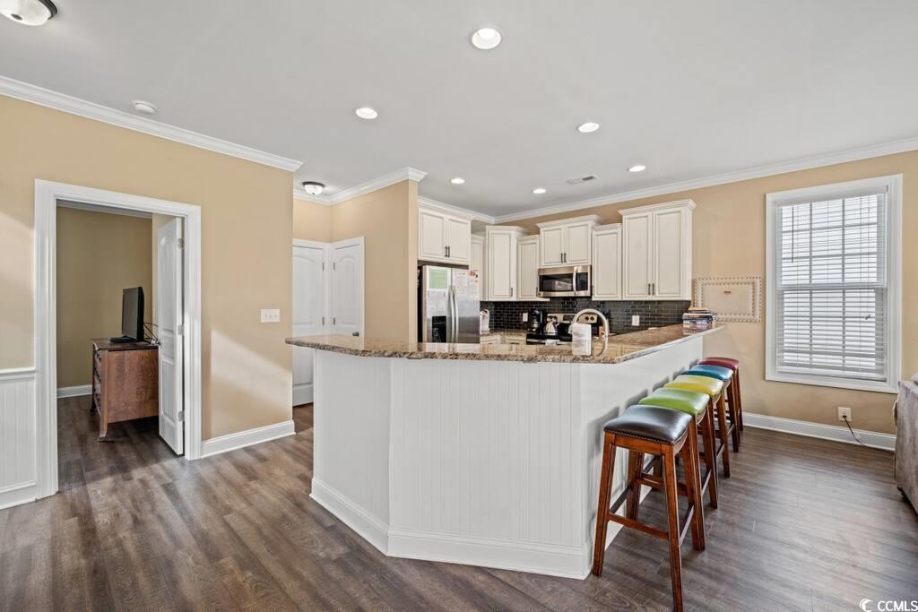 520 Caribbean Way Myrtle Beach, SC 29577 - Photo 4 of 21 Kitchen featuring light stone counters, stainless steel appliances, a breakfast bar, ornamental molding, and recessed lighting