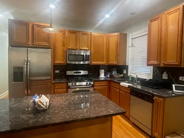 a kitchen with kitchen island granite countertop a sink stove and refrigerator
