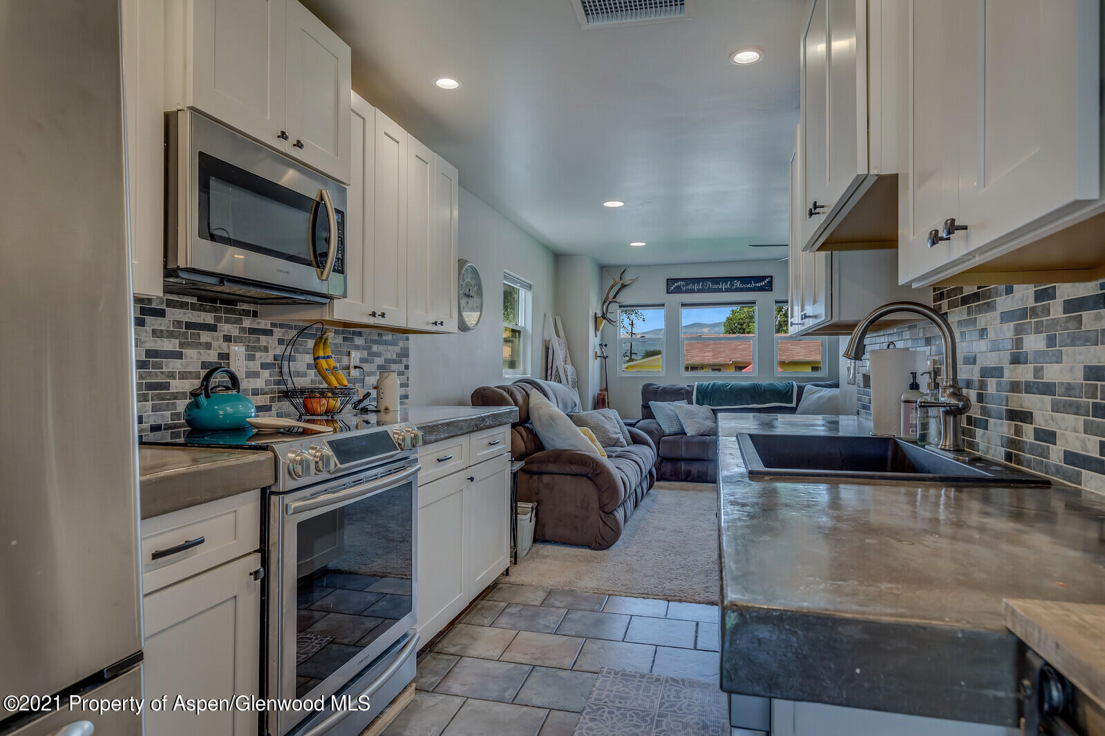 a kitchen with stainless steel appliances granite countertop a stove top oven a sink dishwasher and white cabinets with wooden floor