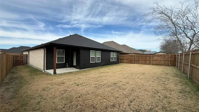 a view of a house with a yard and wooden fence