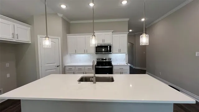 a kitchen with kitchen island a sink stainless steel appliances and white cabinets