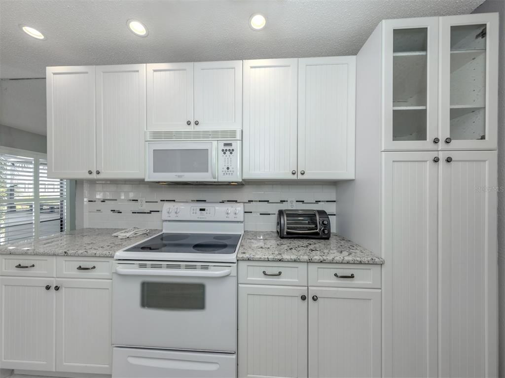 1555 Tarpon Center Drive, Unit 255 Venice, FL 34285 - Photo 19 of 57 a kitchen with granite countertop white cabinets and white appliances