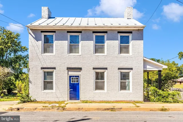 a view of a brick house with a yard and large tree