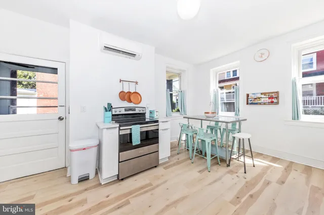 a kitchen with a stove and white cabinets with wooden floor