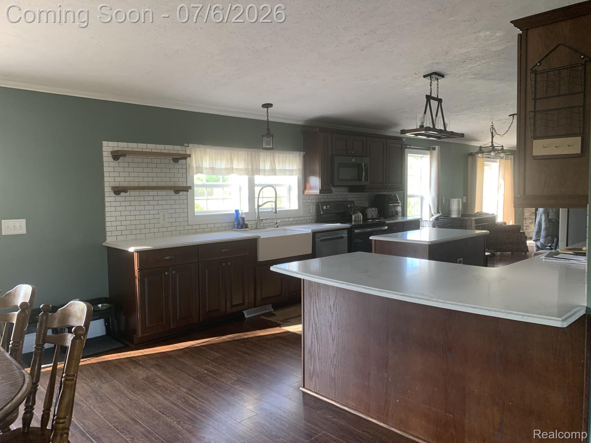 4168 Harris Road Fort Gratiot, MI 48059 - Photo 16 of 30 Kitchen featuring wood-finish flooring, dark wood cabinetry, white subway tile backsplash, and light-toned countertops