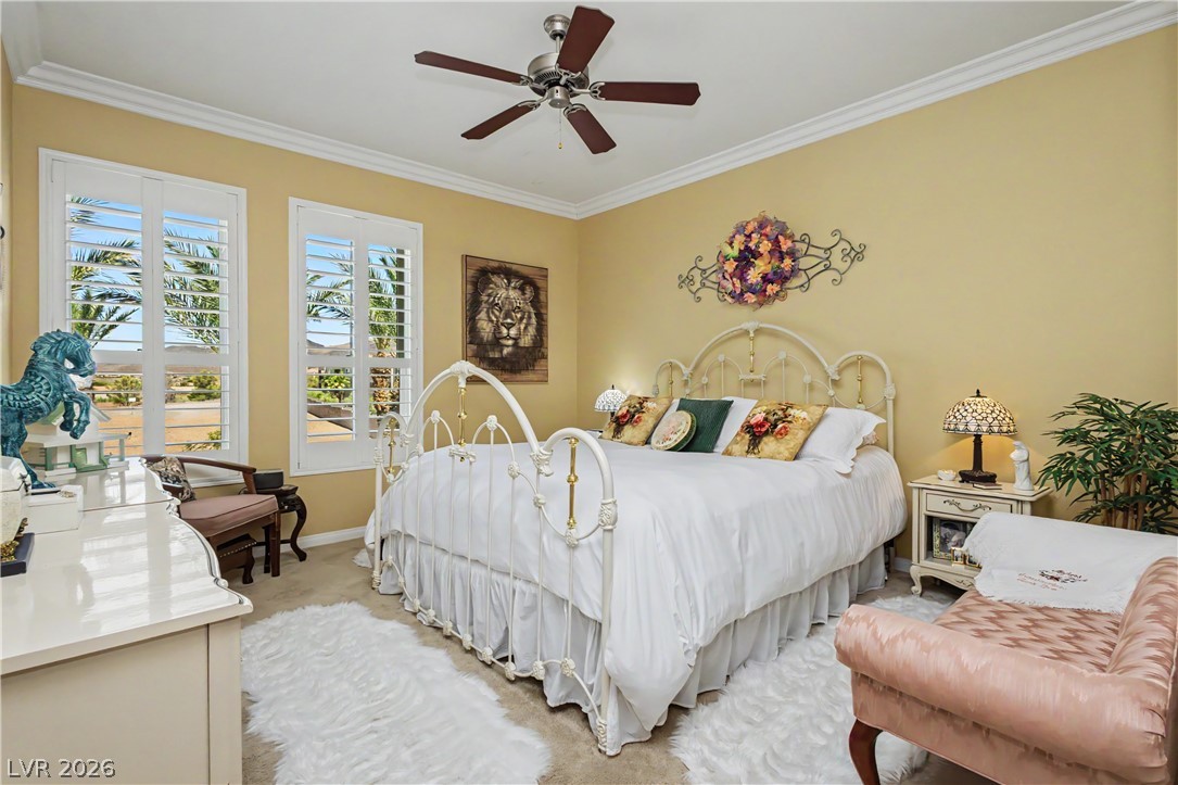 2555 Hampton Road, Unit 3308 Henderson, NV 89052 - Photo 35 of 65 Ornate bedframe grounds a tranquil bedroom with shuttered windows overlooking a natural landscape.