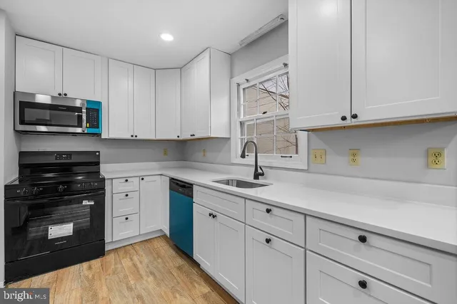 a kitchen with white cabinets and appliances