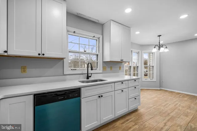 a kitchen with stainless steel appliances granite countertop a sink dishwasher a stove and white cabinets with wooden floor