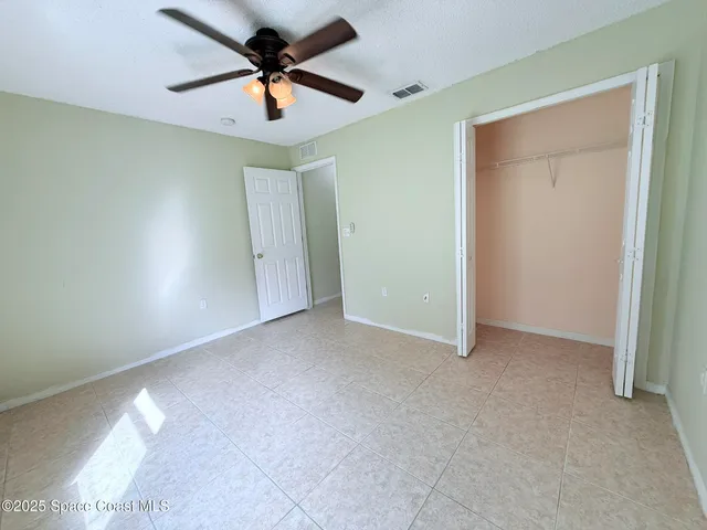 a view of a room with a ceiling fan and carpet