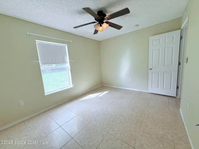 an empty room with windows and fan