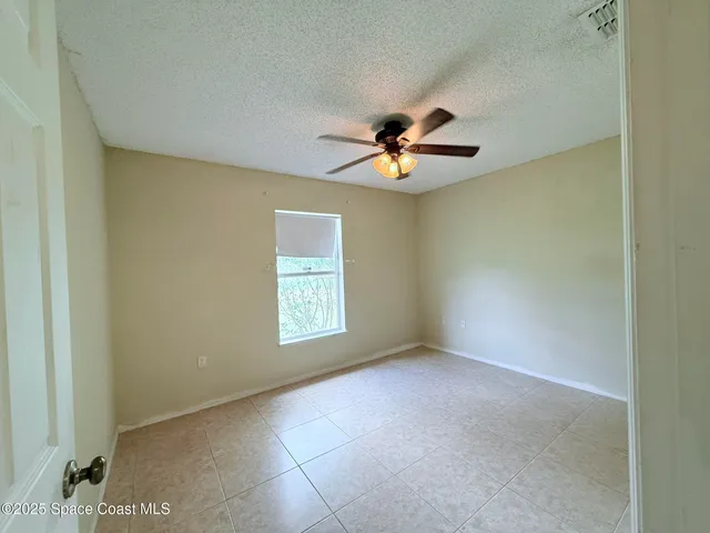 an empty room with windows and fan