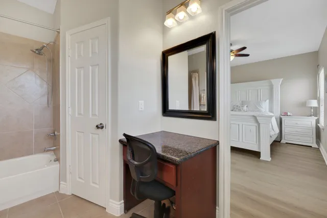 a bathroom with a granite countertop sink and mirror with bathtub