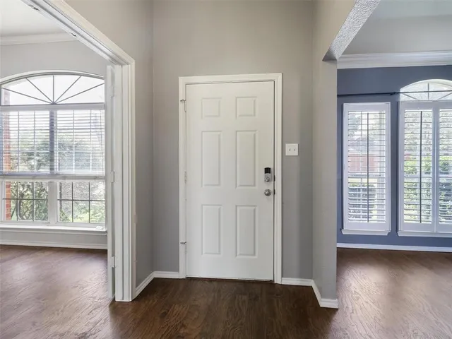 an empty room with wooden floor and windows with curtains view
