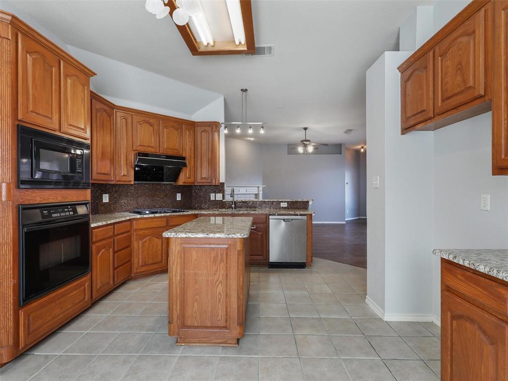 5628 Rock Canyon Road The Colony, TX 75056 - Photo 10 of 24 a large kitchen with stainless steel appliances granite countertop a stove top oven a sink dishwasher and a refrigerator