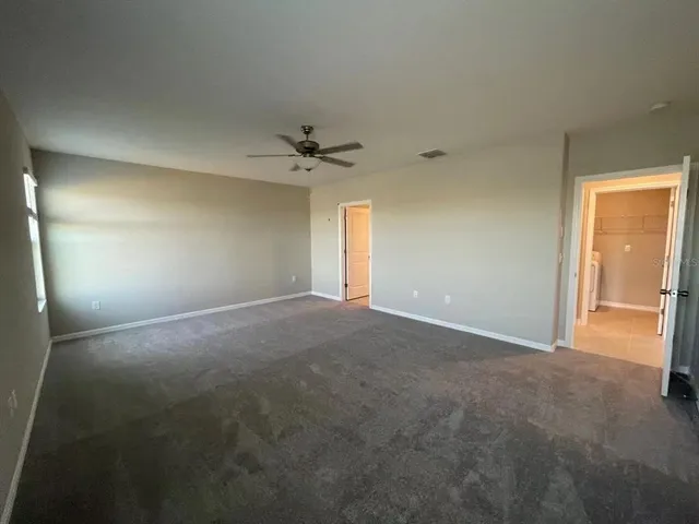 a view of an empty room with a chandelier fan
