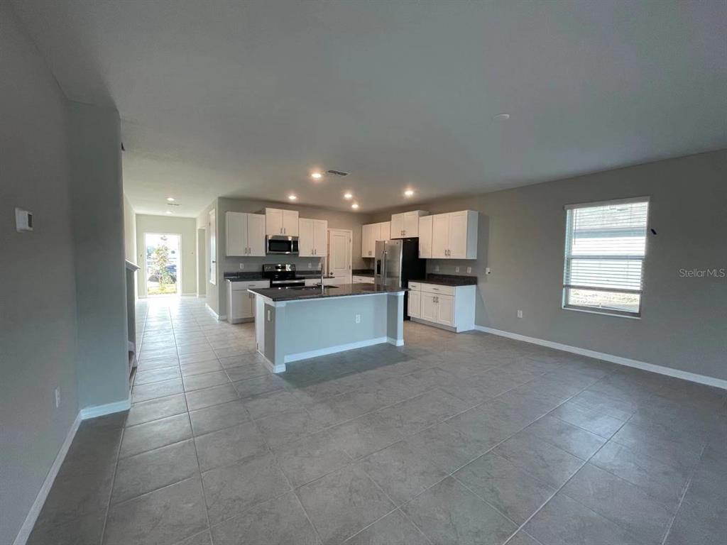 31875 Sun Kettle Loop Wesley Chapel, FL 33545 - Photo 8 of 23 a view of kitchen with kitchen island granite countertop a stove top oven a sink a dining table and chairs
