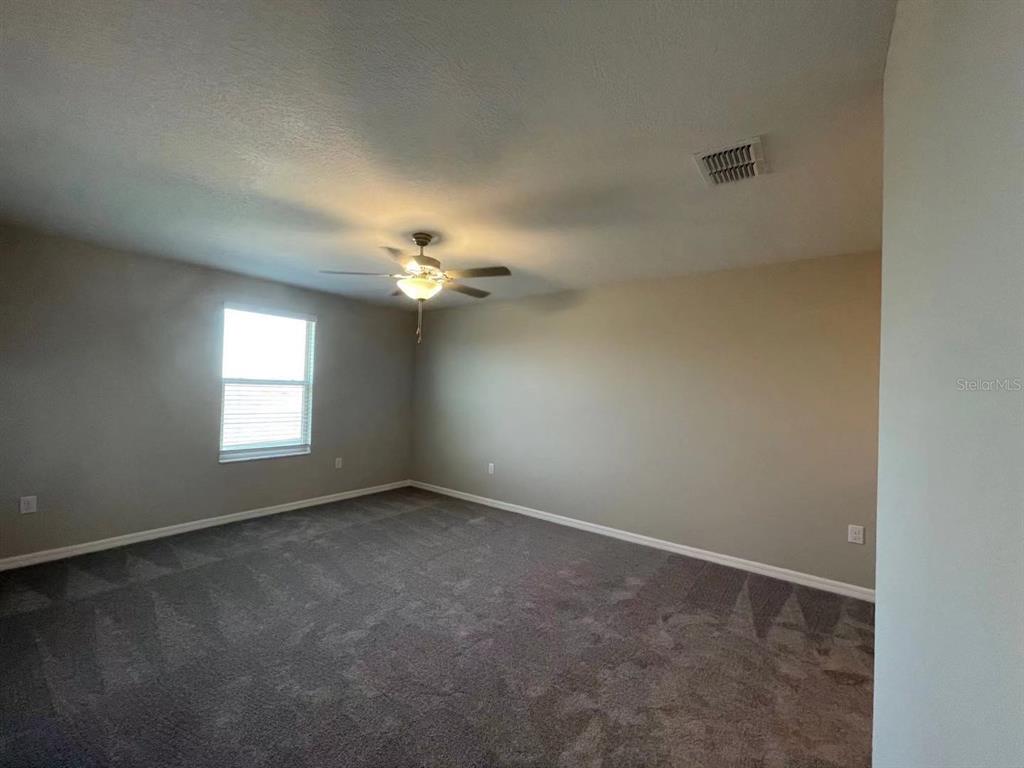 31875 Sun Kettle Loop Wesley Chapel, FL 33545 - Photo 9 of 23 en empty room with windows and chandelier fan