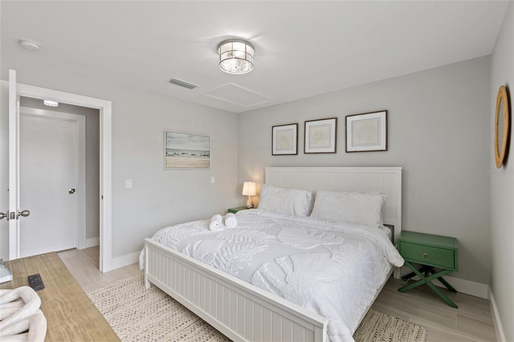 110 Spring Avenue Anna Maria, FL 34216 - Photo 12 of 62 a bedroom with a bed and a chandelier