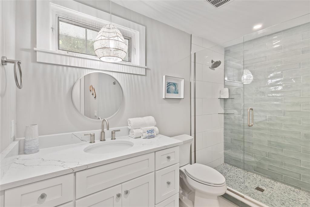 110 Spring Avenue Anna Maria, FL 34216 - Photo 16 of 62 a bathroom with a granite countertop toilet a sink a mirror a shower a vanity and window