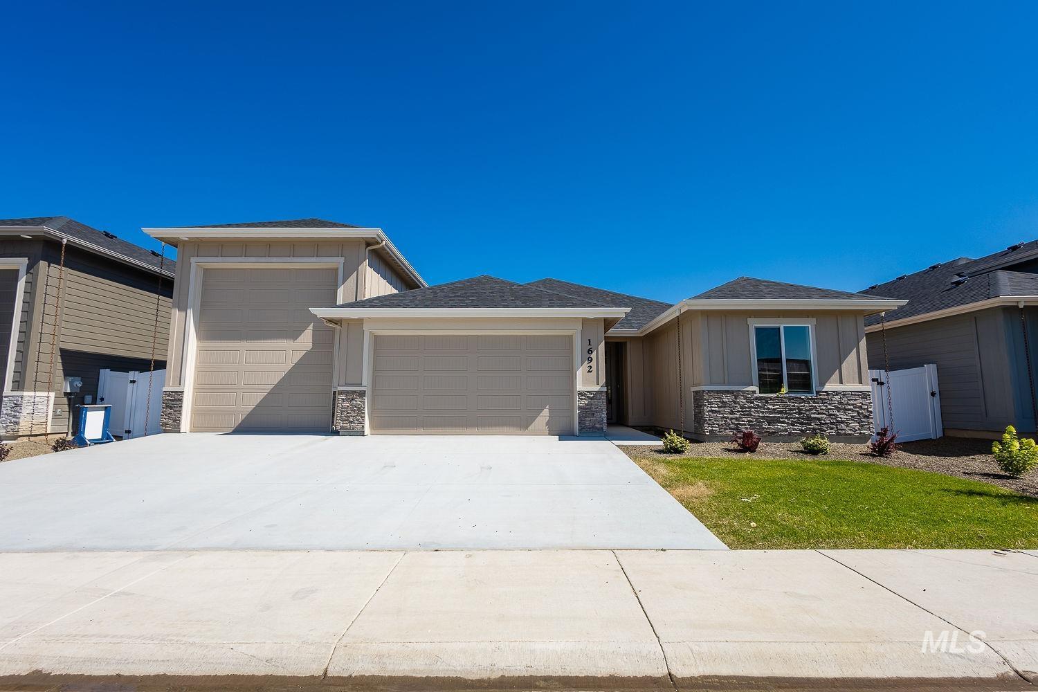 Prairie-style home with stone siding, a garage, driveway, and board and batten siding