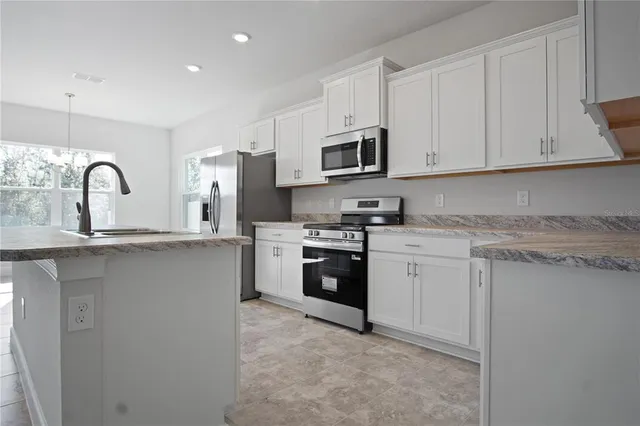 a kitchen with stainless steel appliances granite countertop a stove a sink dishwasher and a refrigerator
