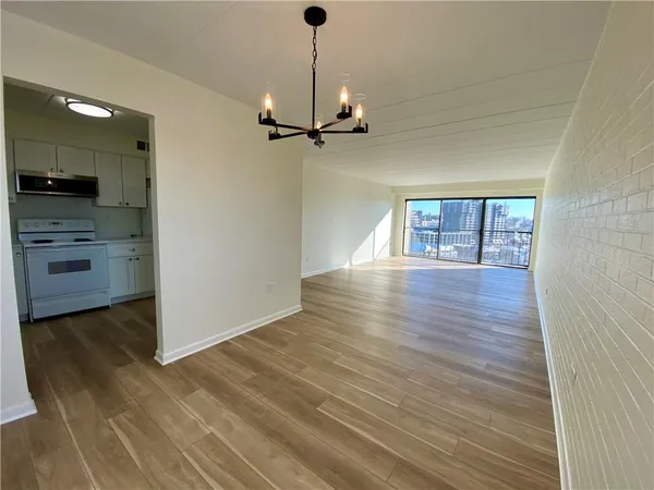a view of an empty room with a window and wooden floor