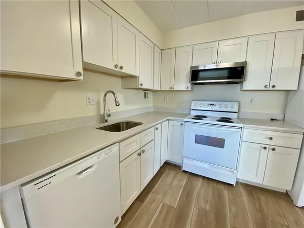 a kitchen with granite countertop white cabinets and white appliances